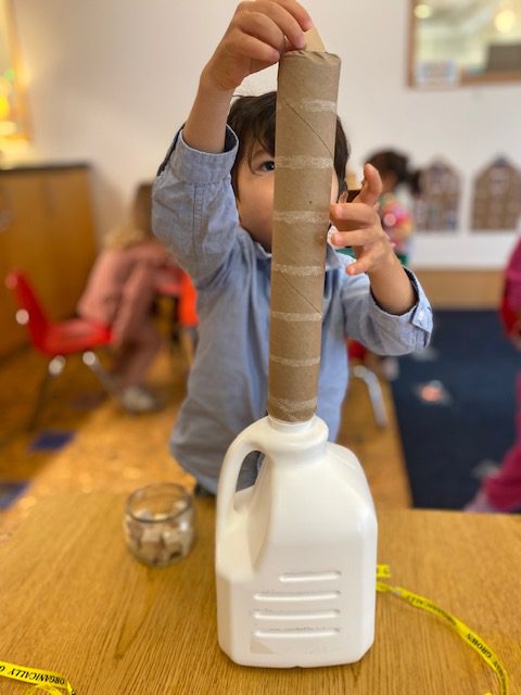 A child dropping something through a tube into a container